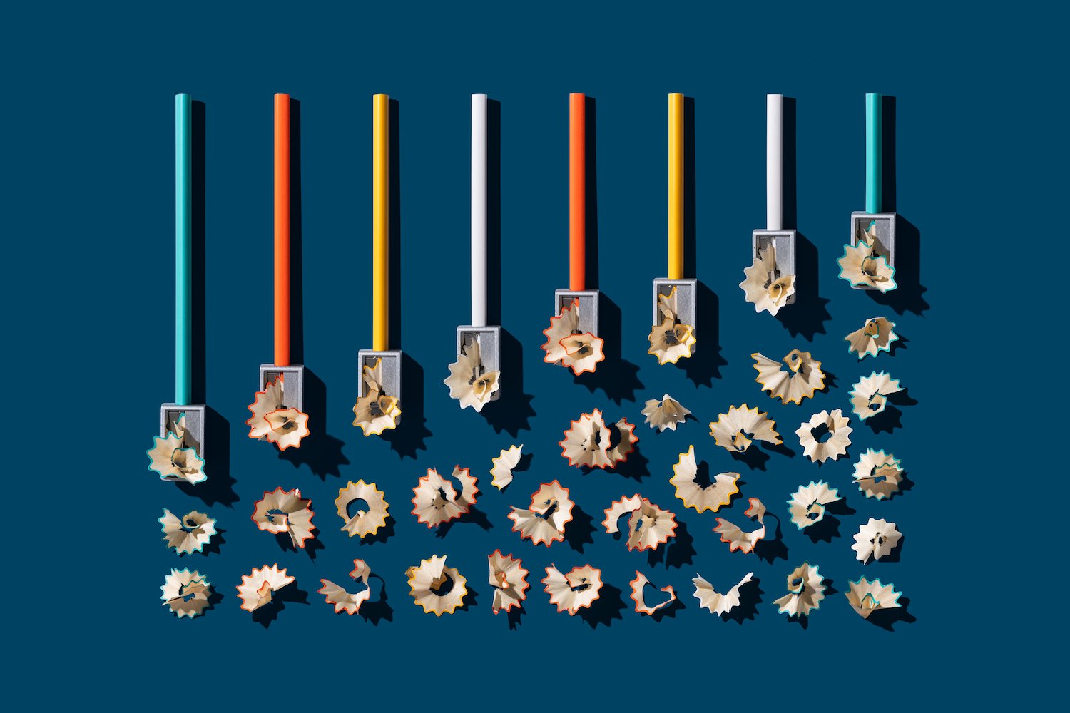 Pencil Sharpener Sharpening Pencils with Pencil Shavings on Solid Blue Colored Background.